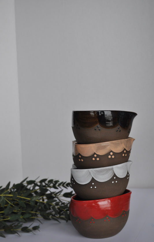 Stack of ceramic pots with different color finishes on a white surface.