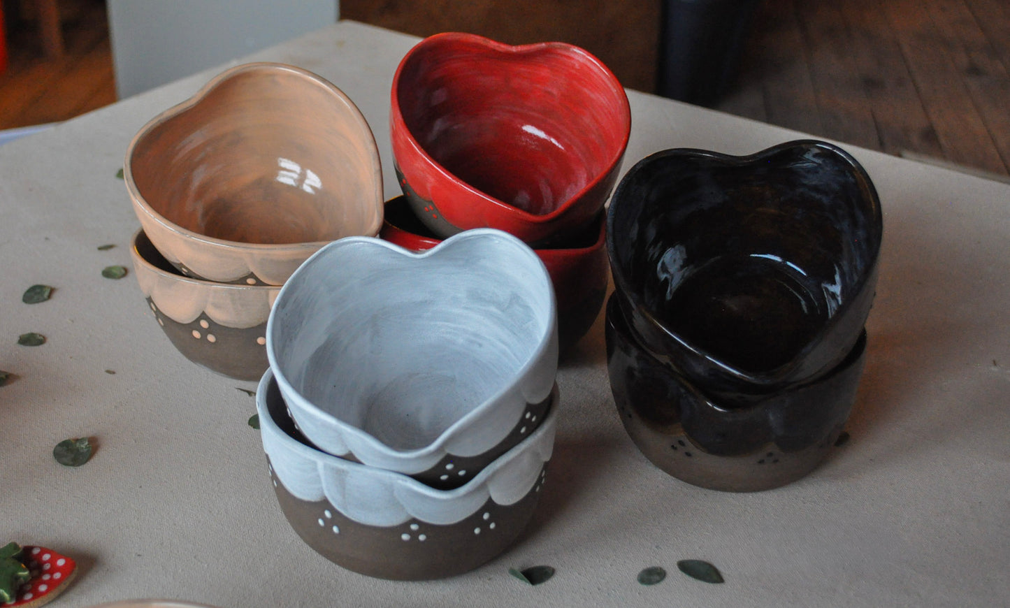 Set of heart-shaped ceramic bowls in various colors on a surface.