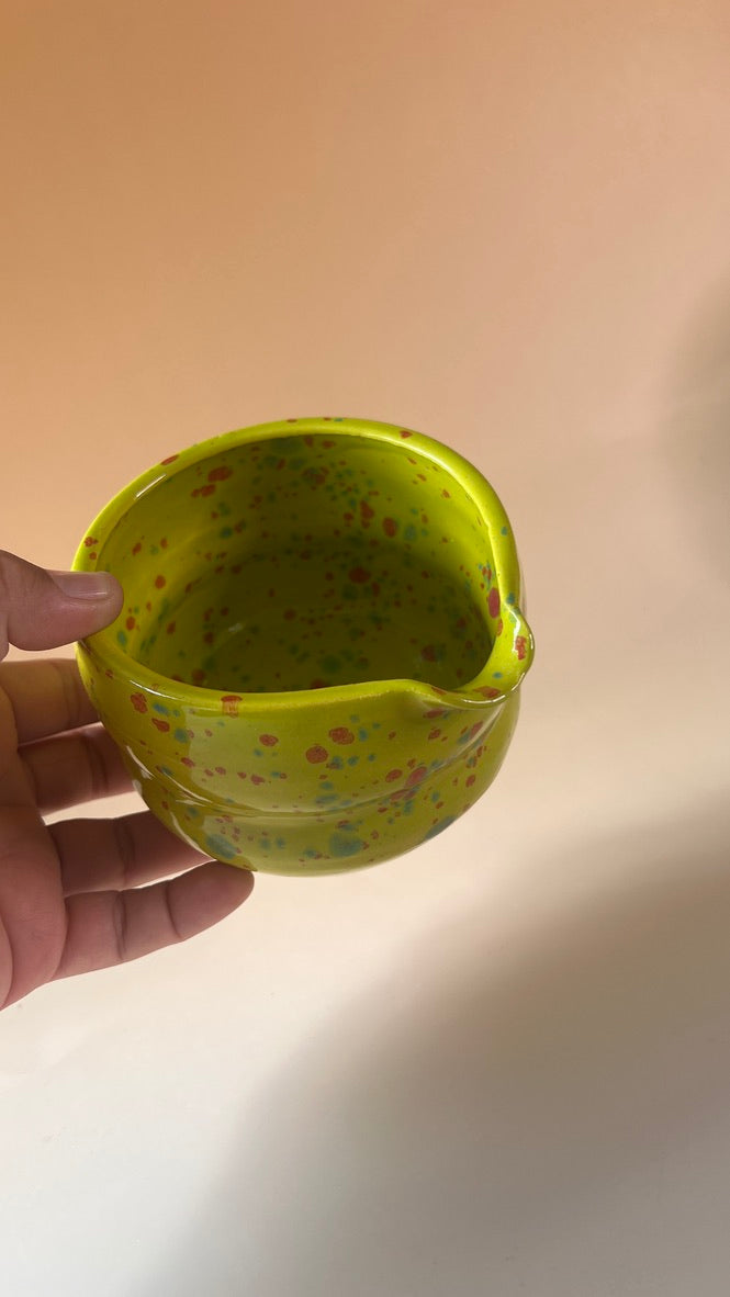 Hand holding a green neon textured container against a plain background