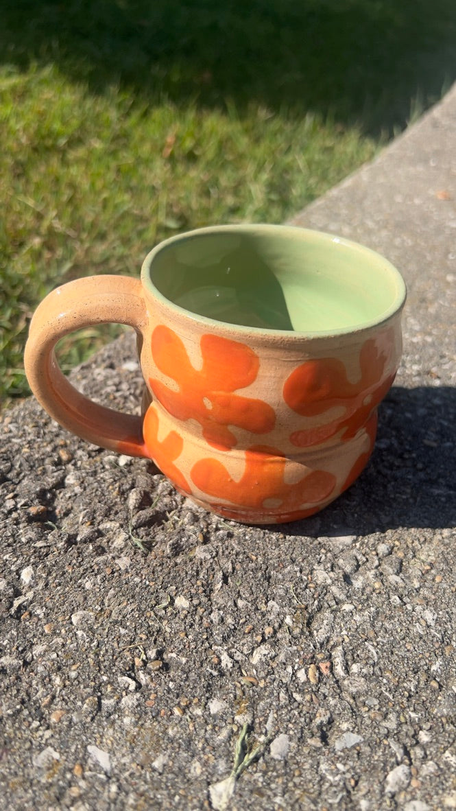 Ceramic mug with orange pattern on a concrete surface