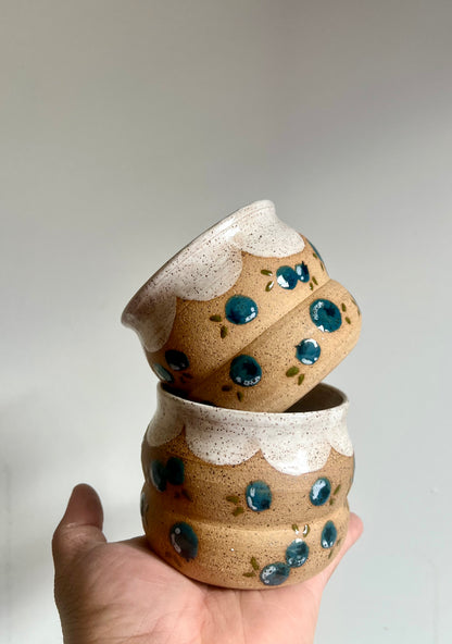 Stack of ceramic cups with speckled design held against a neutral background