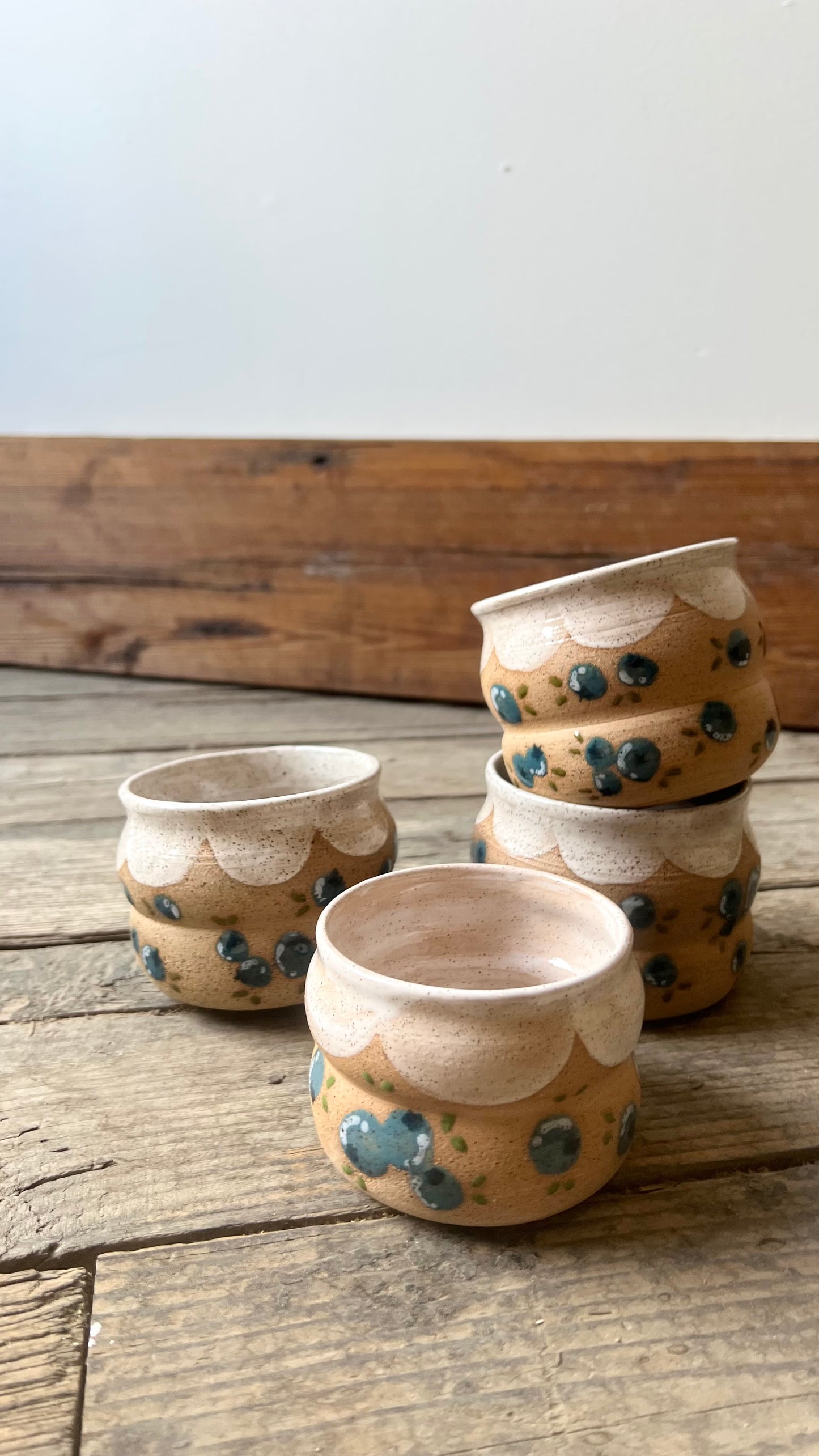 Set of ceramic pots with blue speckles on a wooden surface