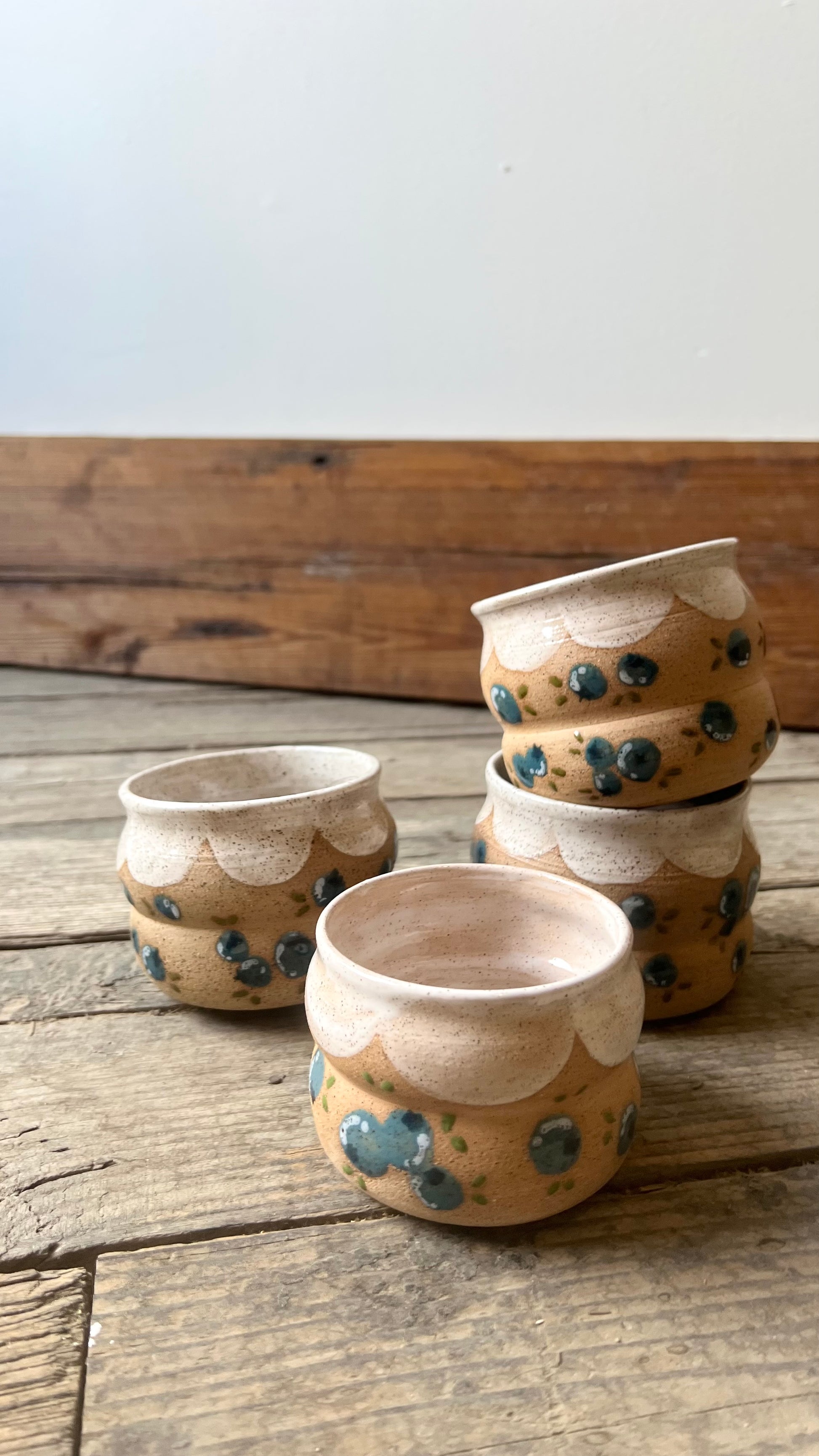 Set of ceramic pots with blue speckles on a wooden surface