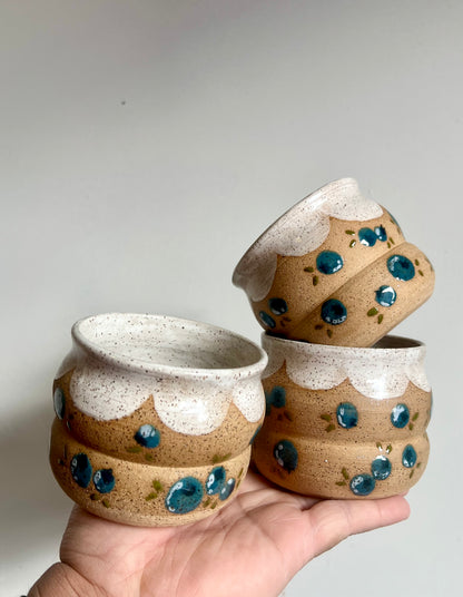 Three ceramic bowls with speckled design held against a plain background