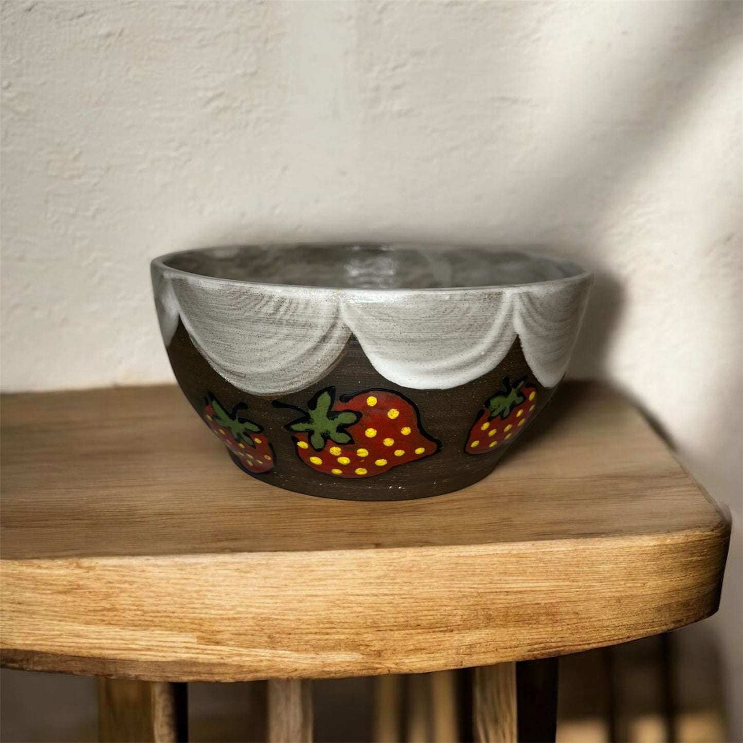 Decorative ceramic bowl with strawberry design on a wooden surface