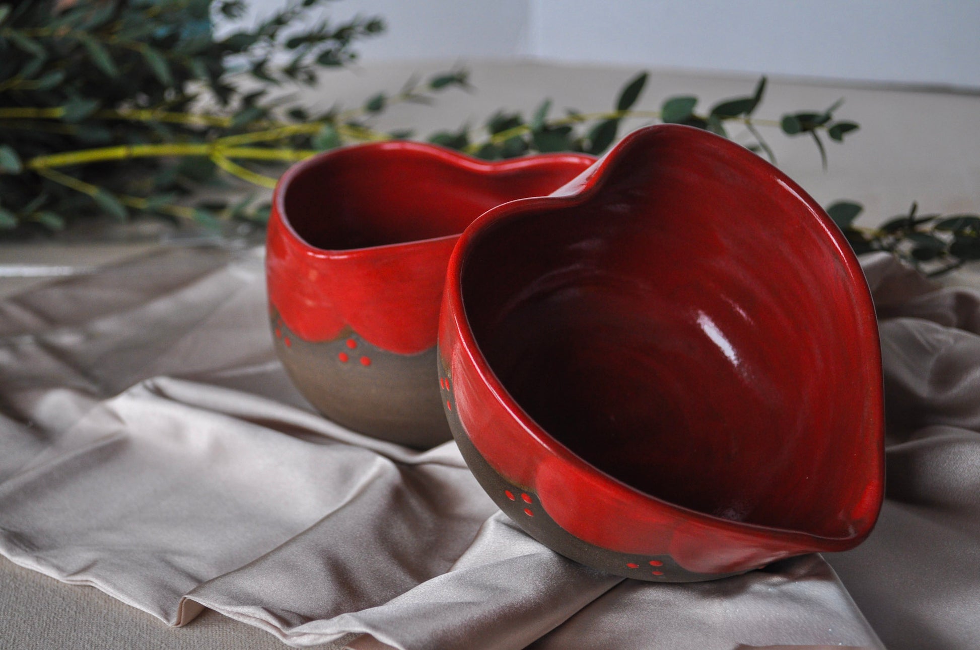 Two red ceramic bowls on a textured surface with a blurred natural background