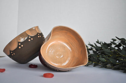 Two ceramic bowls on a light gray surface with greenery in the background