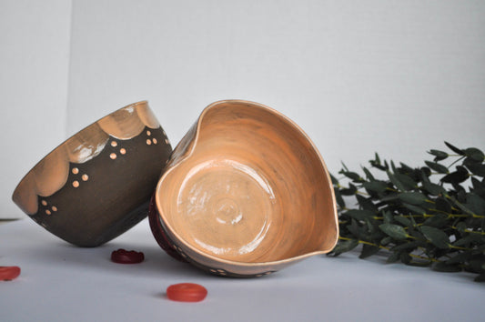 Two ceramic bowls on a light gray surface with greenery in the background