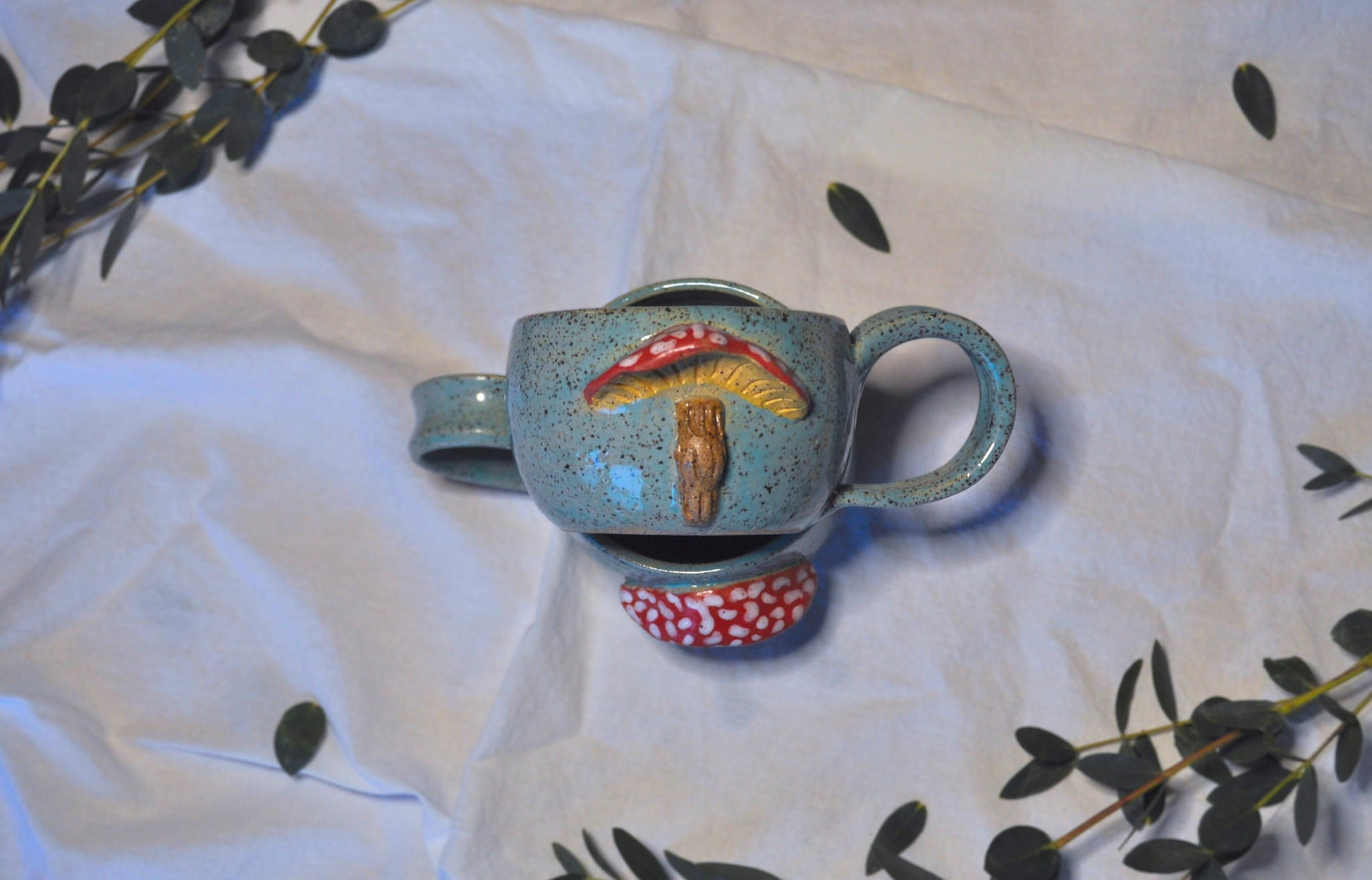 Ceramic mug with mushroom design on a white fabric background