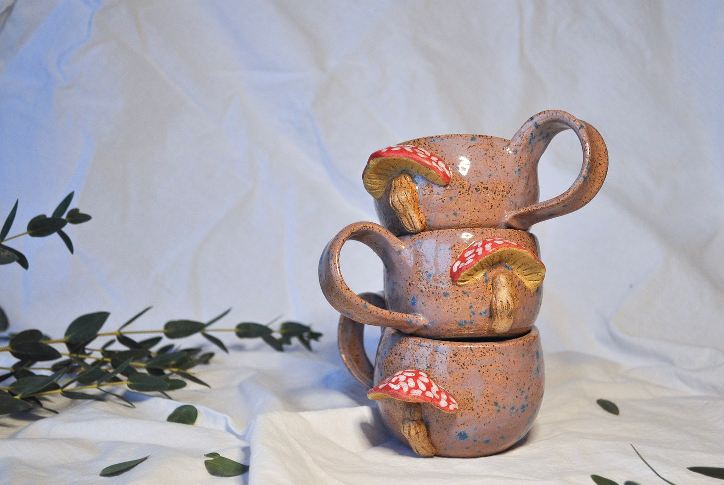 Stack of ceramic cups with mushroom designs on a white background