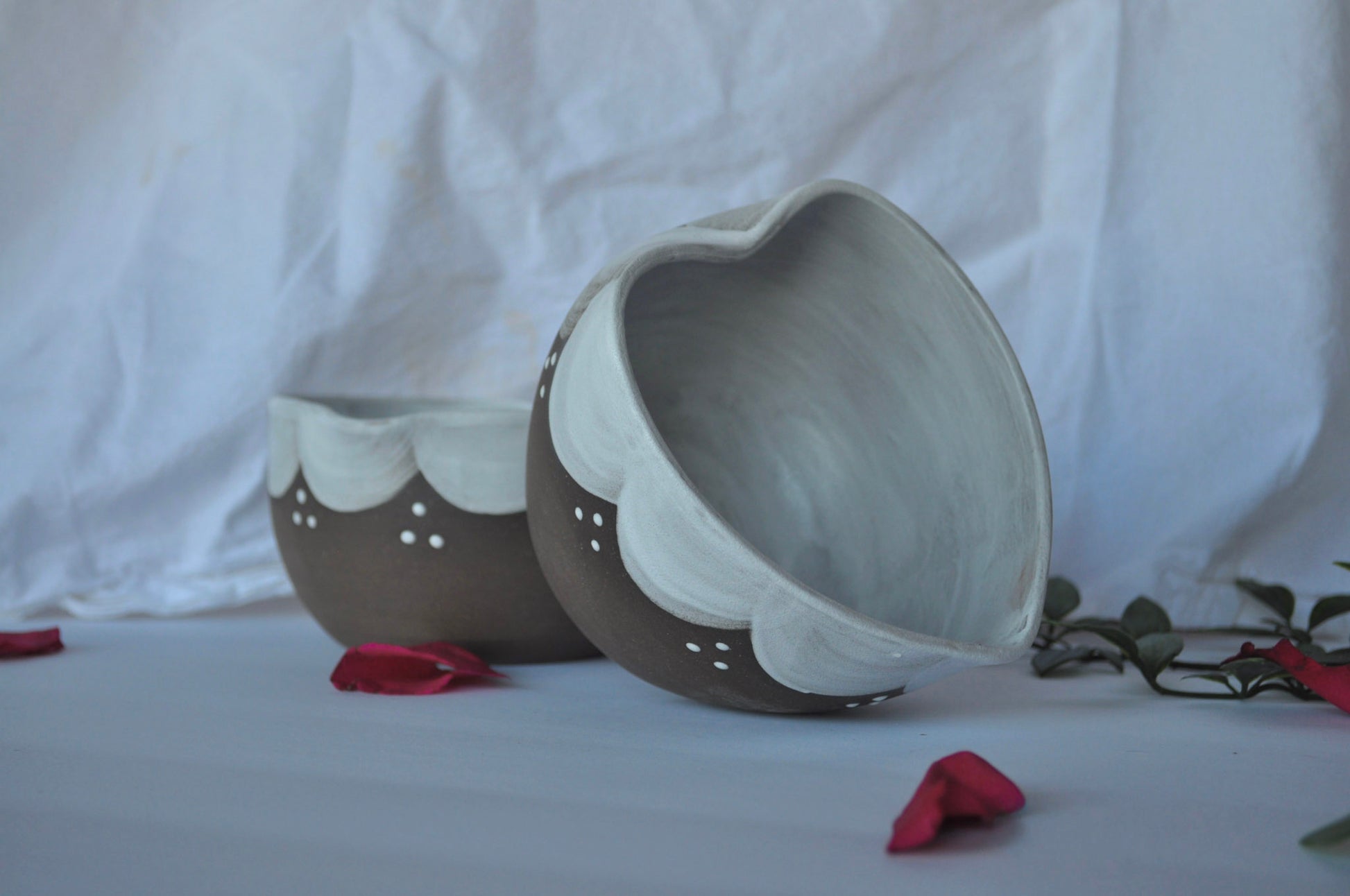 Two ceramic bowls on a white surface with a white curtain background