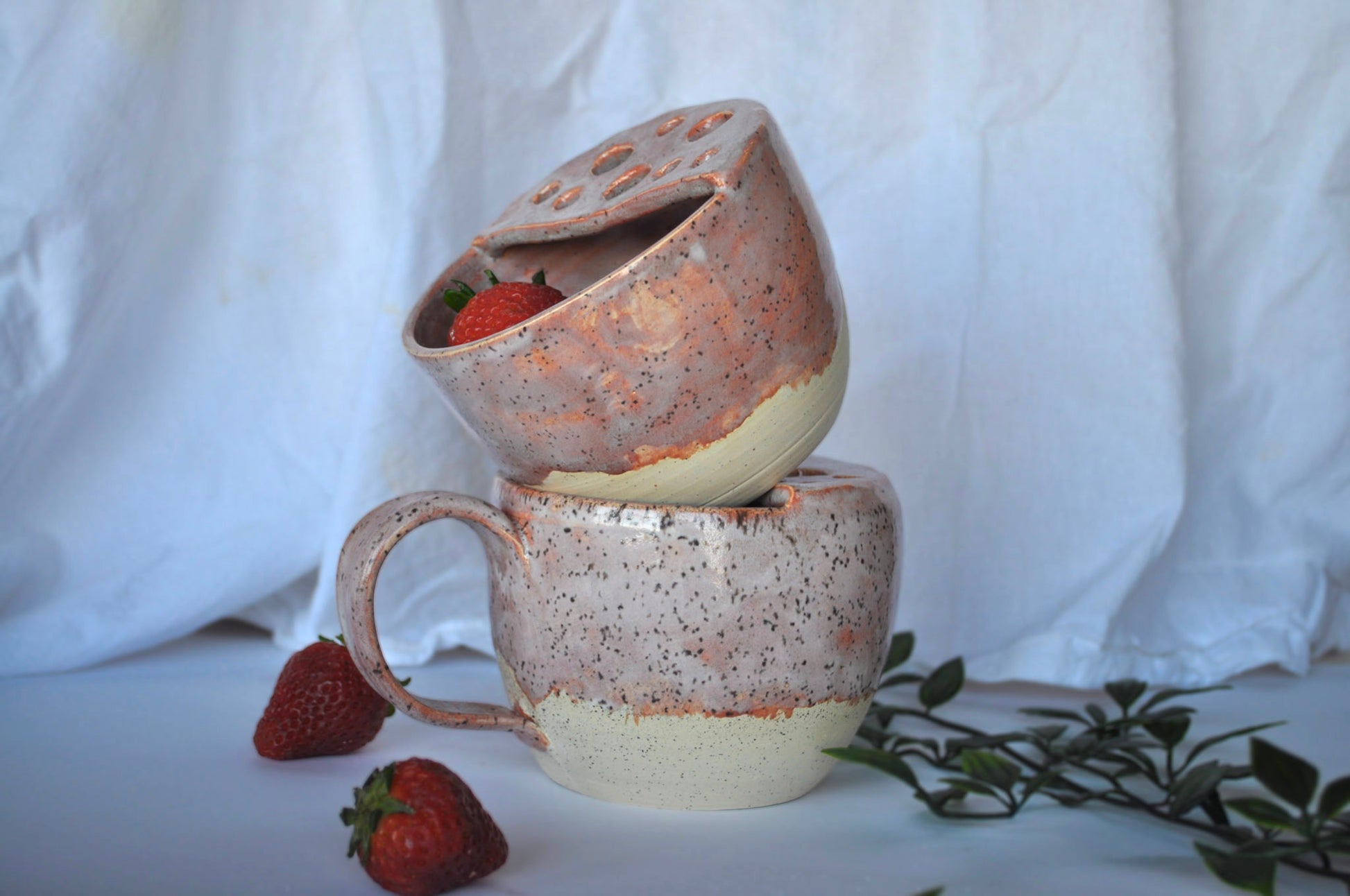 Speckled ceramic mug with a matching pot on a white background