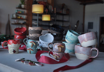 Collection of ceramic mugs and bowls on a table with a blurred background