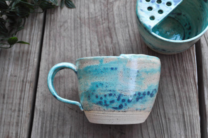 Handmade ceramic mug with blue and white glaze on a wooden surface