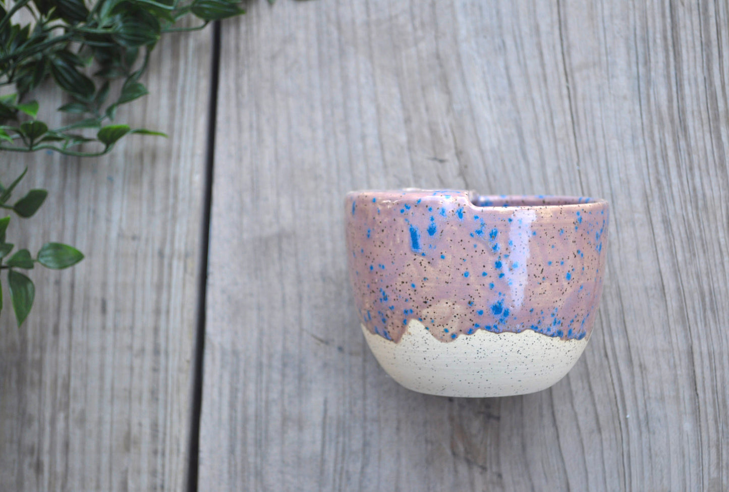 Ceramic cup with speckled design on a wooden surface