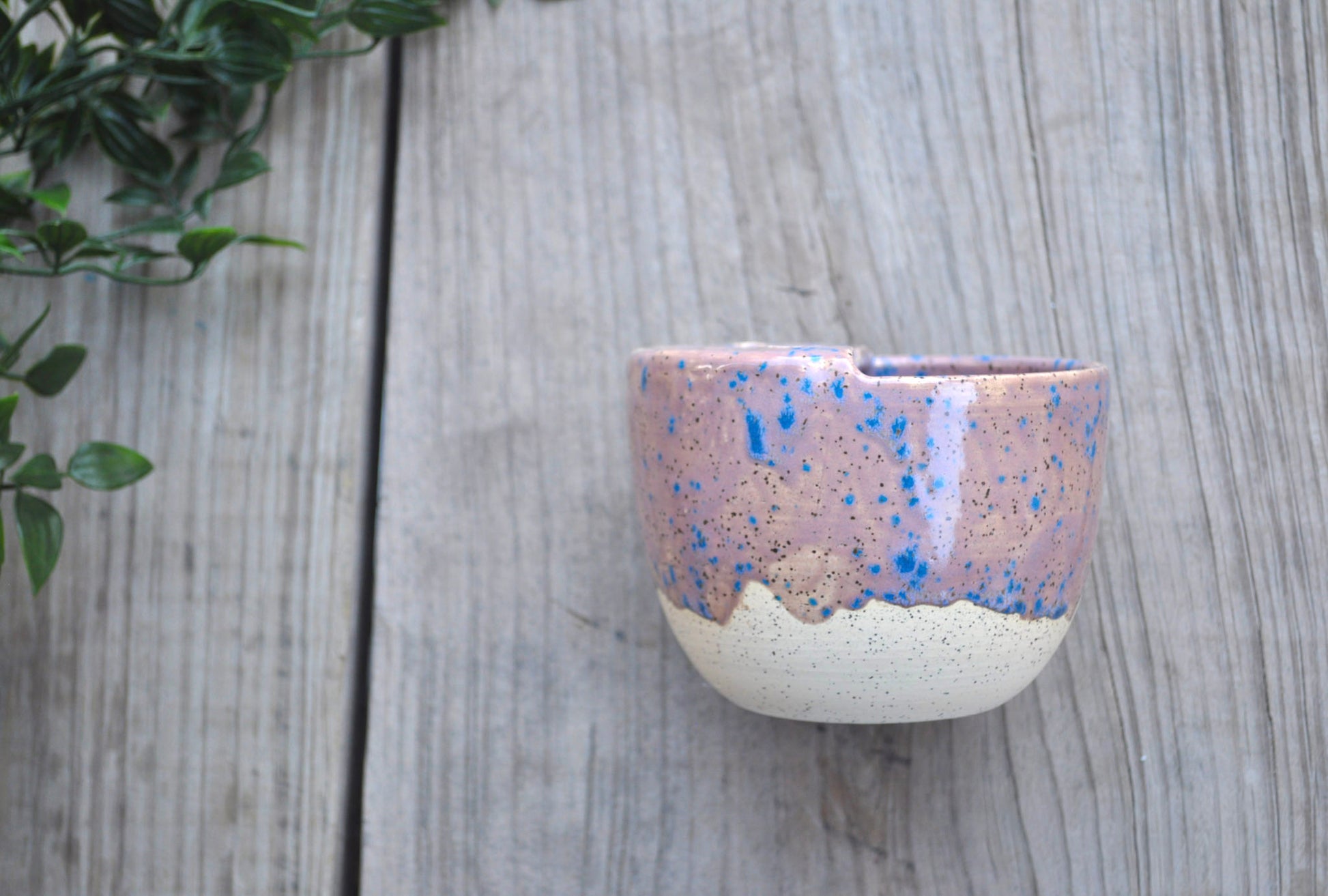 Ceramic cup with speckled design on a wooden surface
