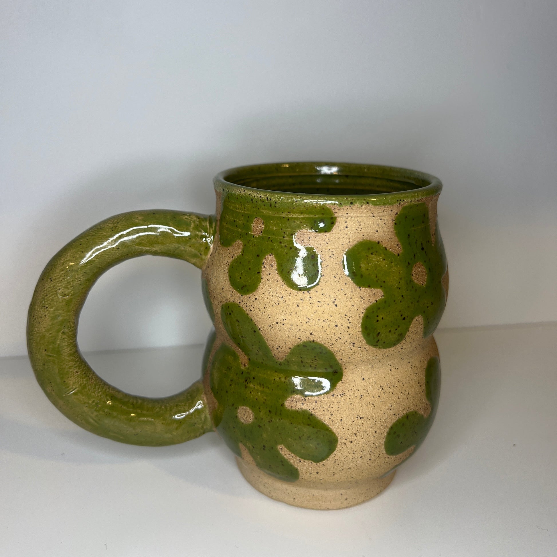 Ceramic mug with green and beige design on a white background