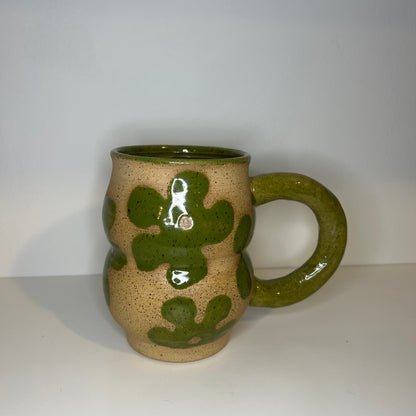Ceramic mug with green floral patterns on a white background