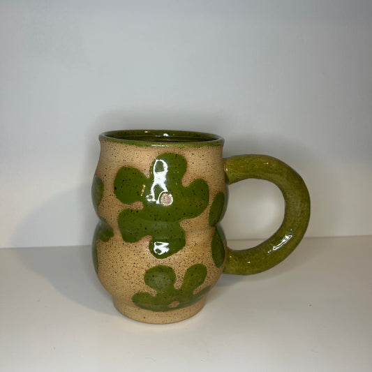 Ceramic mug with green floral patterns on a white background