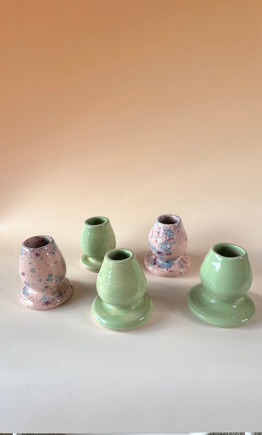 Set of ceramic vases in various colors on a white surface with a beige wall background.