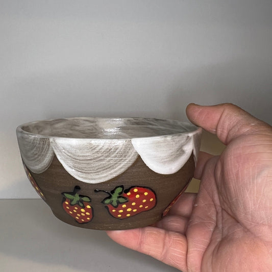 Dark brown ceramic bowl with strawberry designs and added with a white glaze inside and The white rim features a hand-glazed swooping design that adds movement and visual interest. The bowl is on a white background