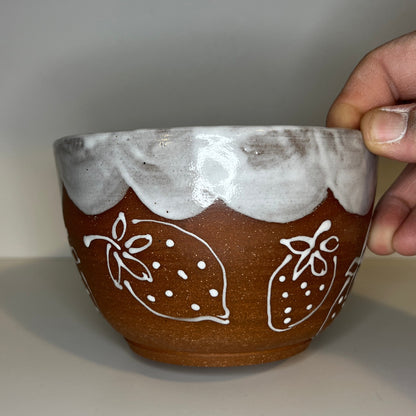 Ceramic bowl with white floral patterns held by a hand against a plain background
