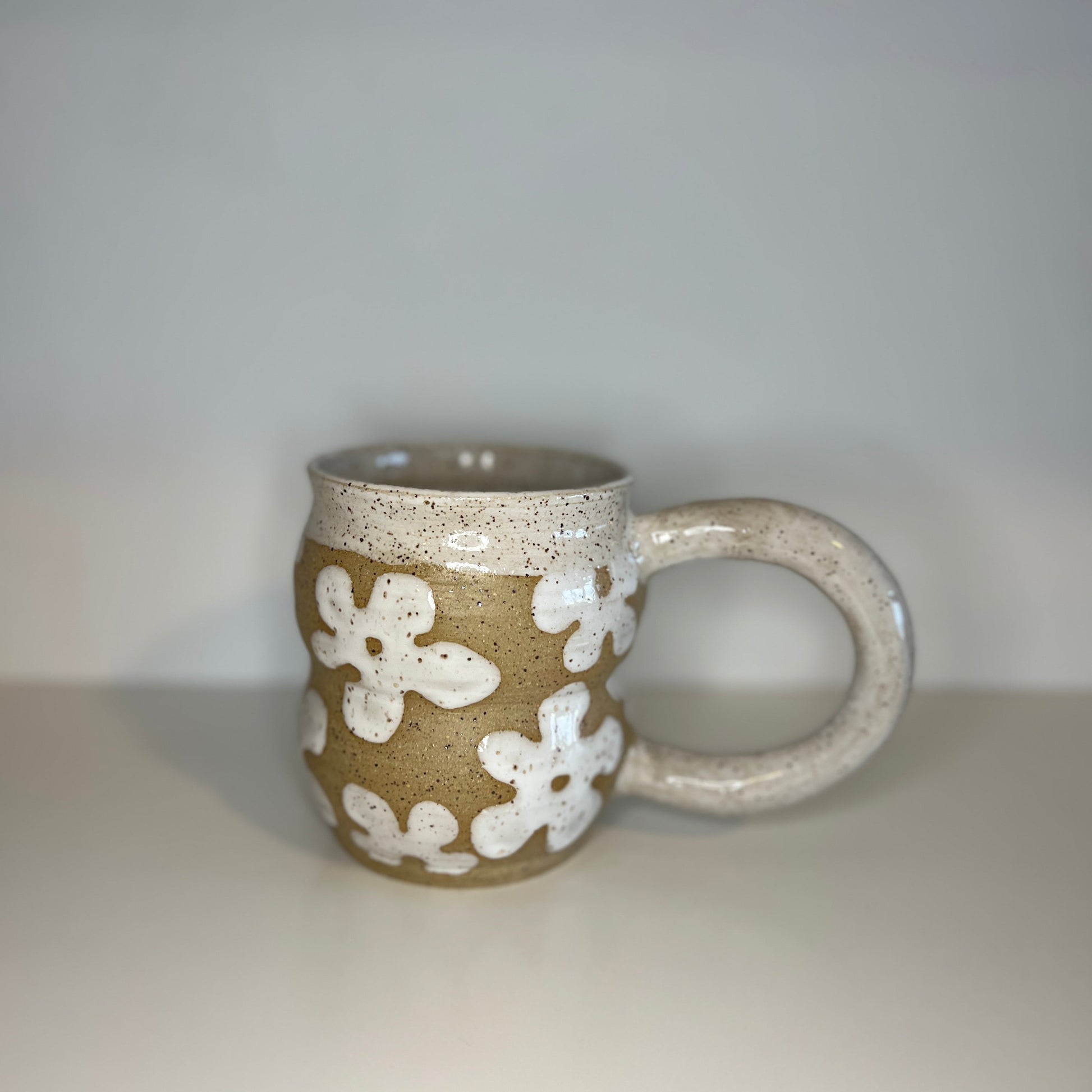 Ceramic mug with white floral patterns on a plain background
