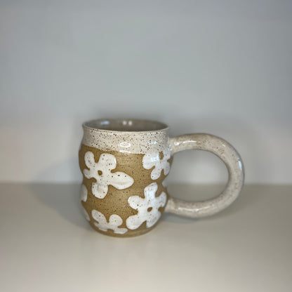 Ceramic mug with white floral patterns on a plain background