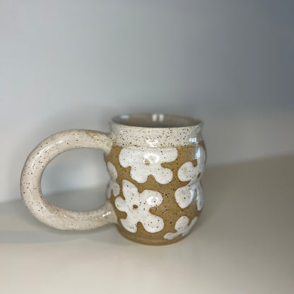 Ceramic mug with white floral patterns on a plain background